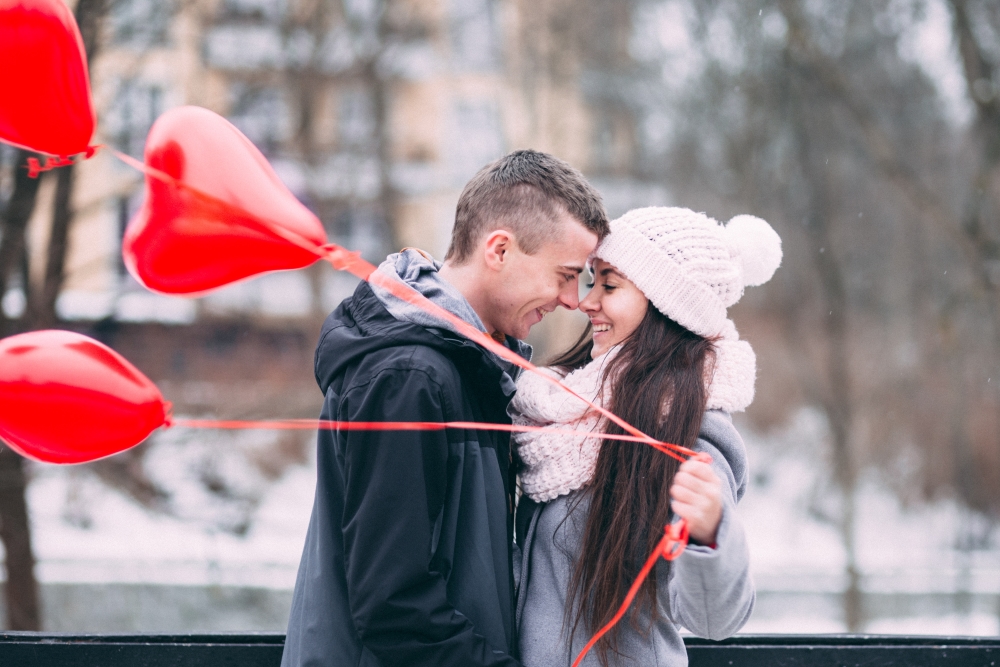 Couple holding heart-shaped balloons.