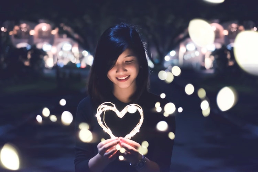 Young woman holding a heart made out of lights