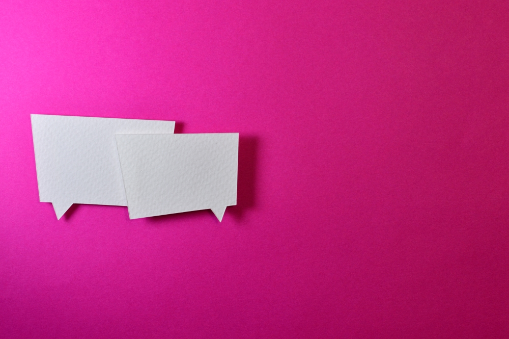 Two paper speech bubbles on a pink background