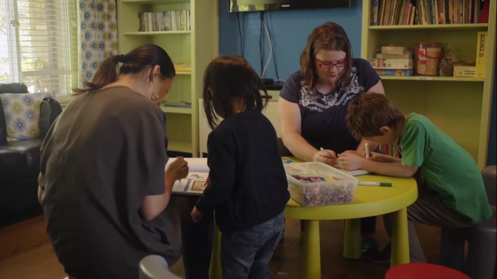 Women make art with children at a table