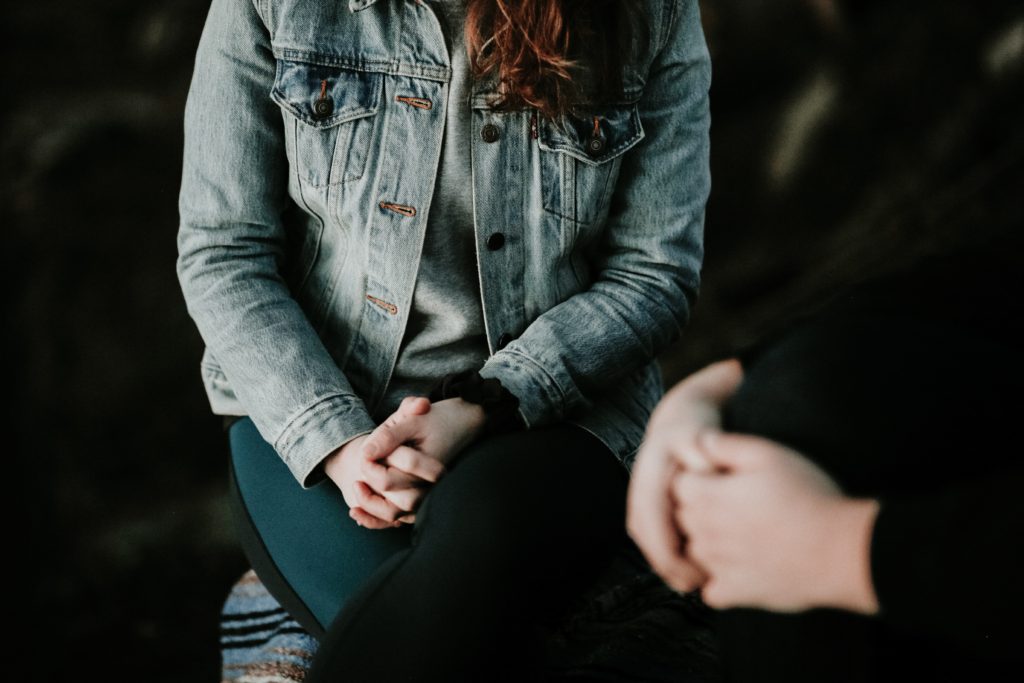 Two women sit with their hands on their laps.