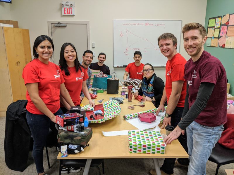 A group of male and female volunteers at the Dixon Society help wrap gifts