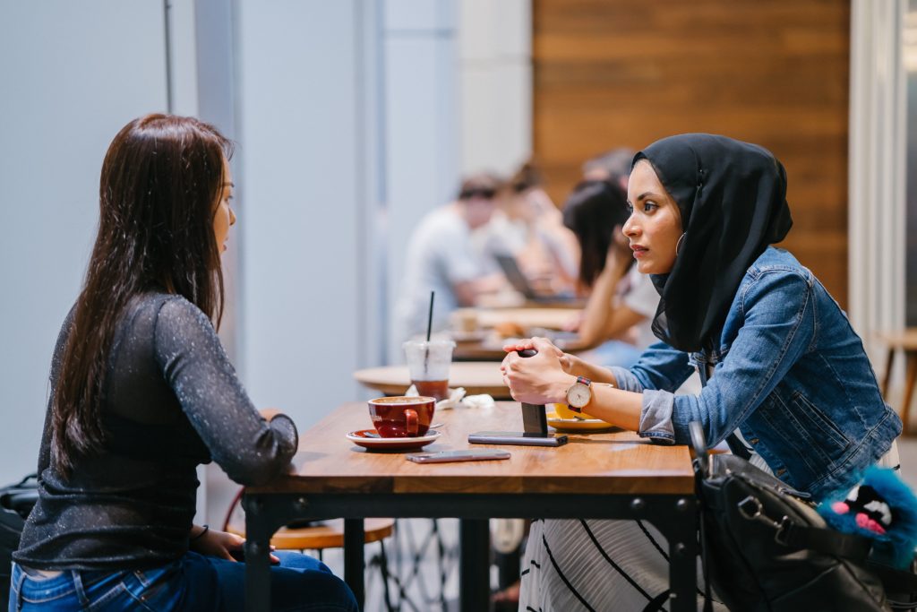 Two women talk at a table