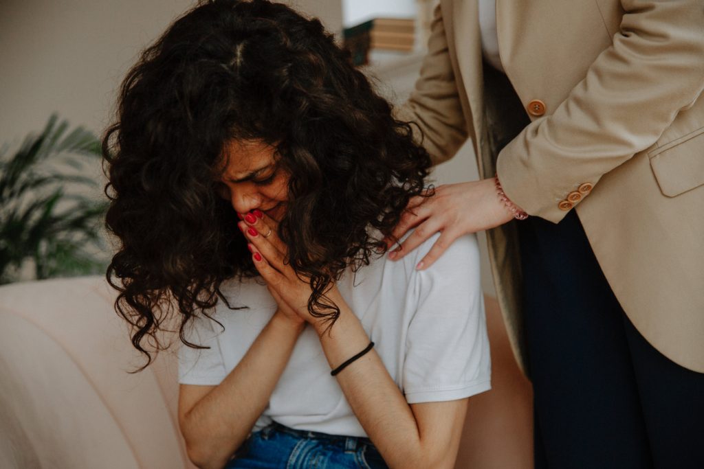 A crying woman is comforted by another woman