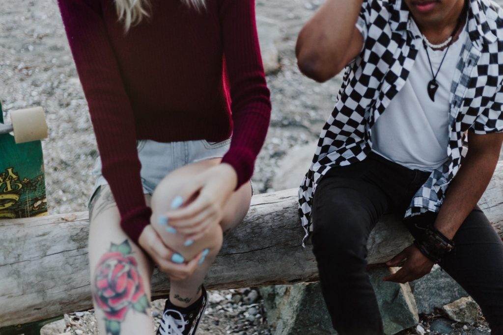 A couple sit on a log at the beach.