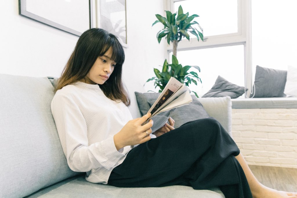 A  woman sits and reads a newspaper