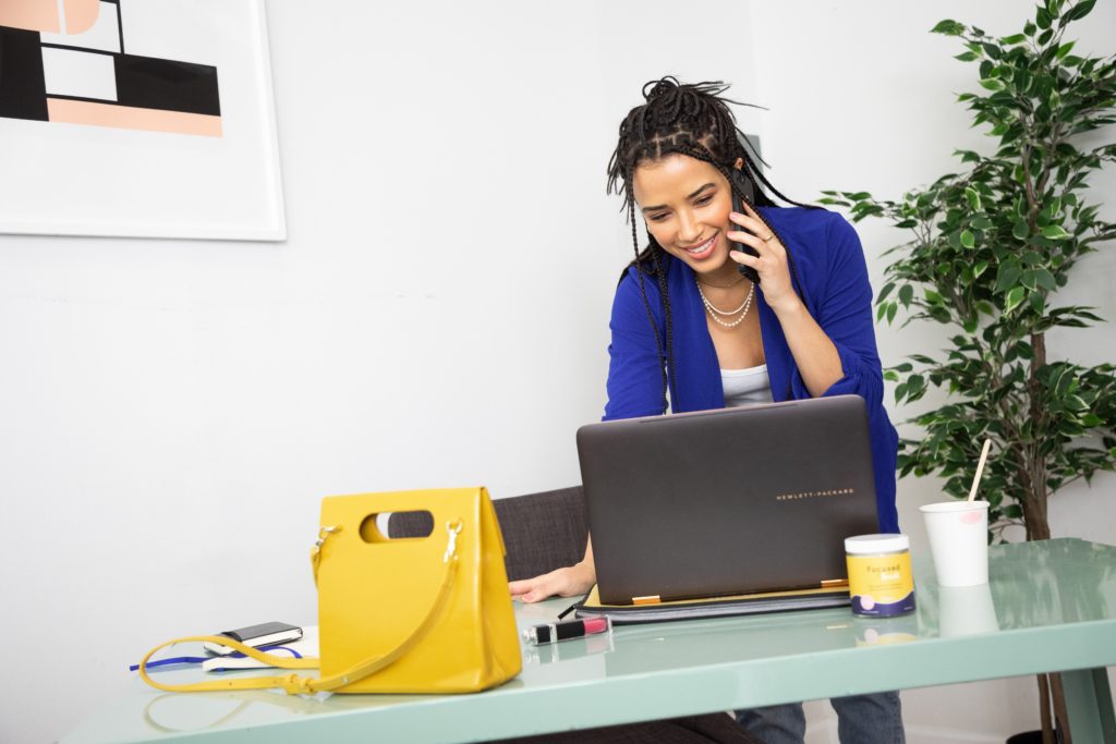 A woman takes a phonecall while working at a desk.